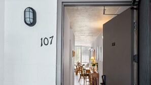 A hallway with the number 107 on the wall, leading to a dining area with wooden furniture and a table lamp. - Alii Villas 107 - Ground Floor Oasis - Vrkcv (Kailua-Kona)