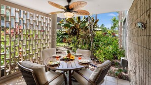 An outdoor patio with a round table, chairs, and a ceiling fan. - Alii Villas 107 - Ground Floor Oasis - Vrkcv (Kailua-Kona)