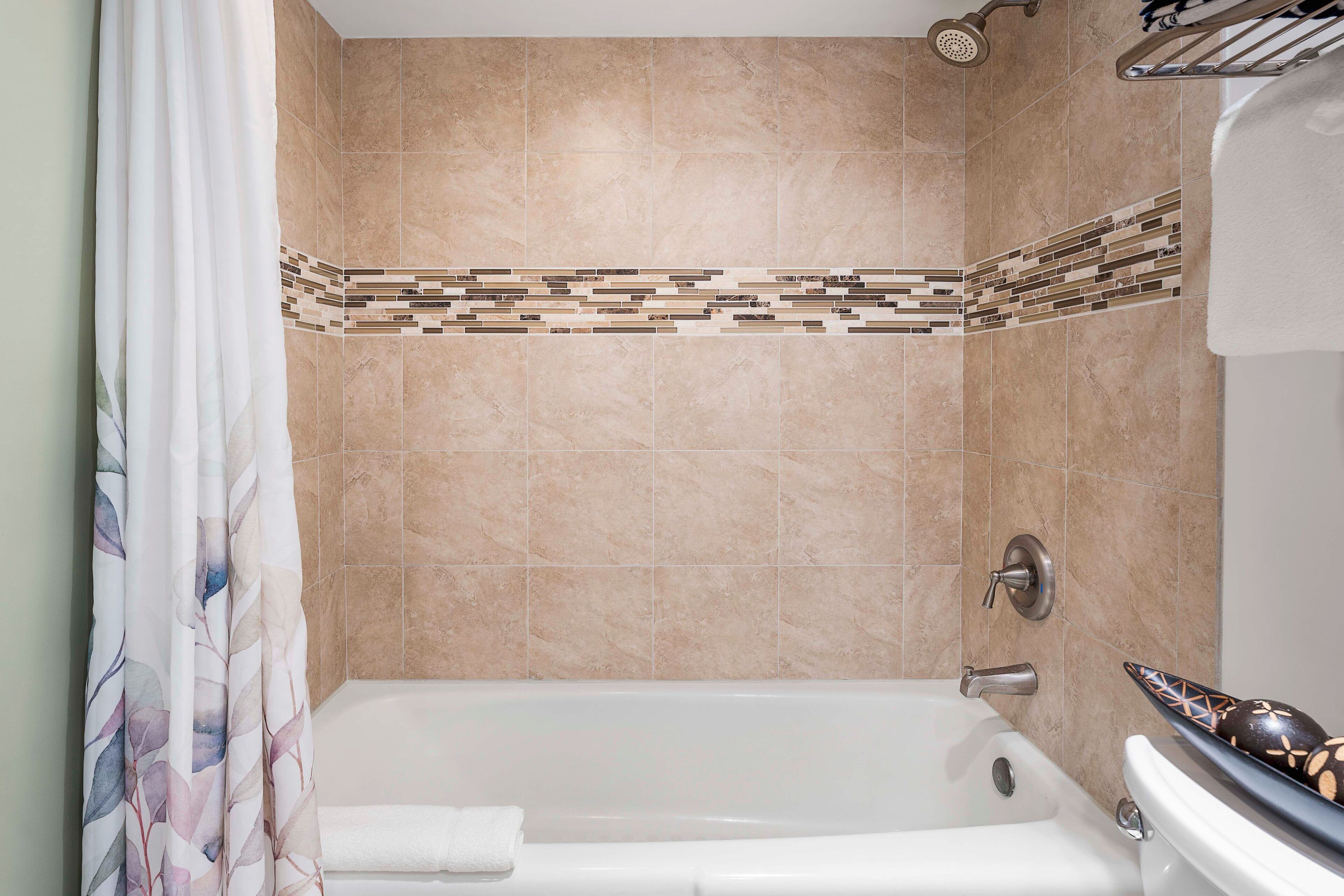 A bathroom with a bathtub, shower, and tiled walls.