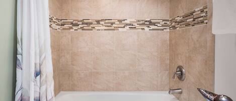 A bathroom with a bathtub, shower, and tiled walls.