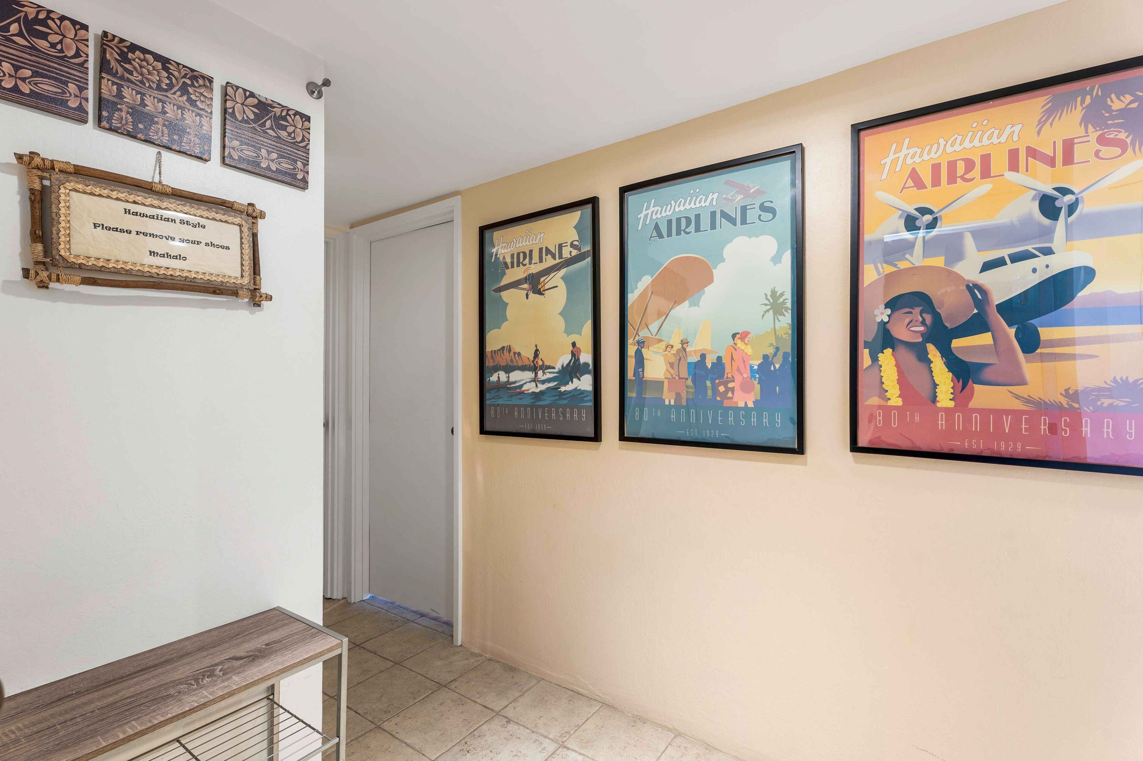 A hallway with framed Hawaiian Airlines posters and a wooden bench.