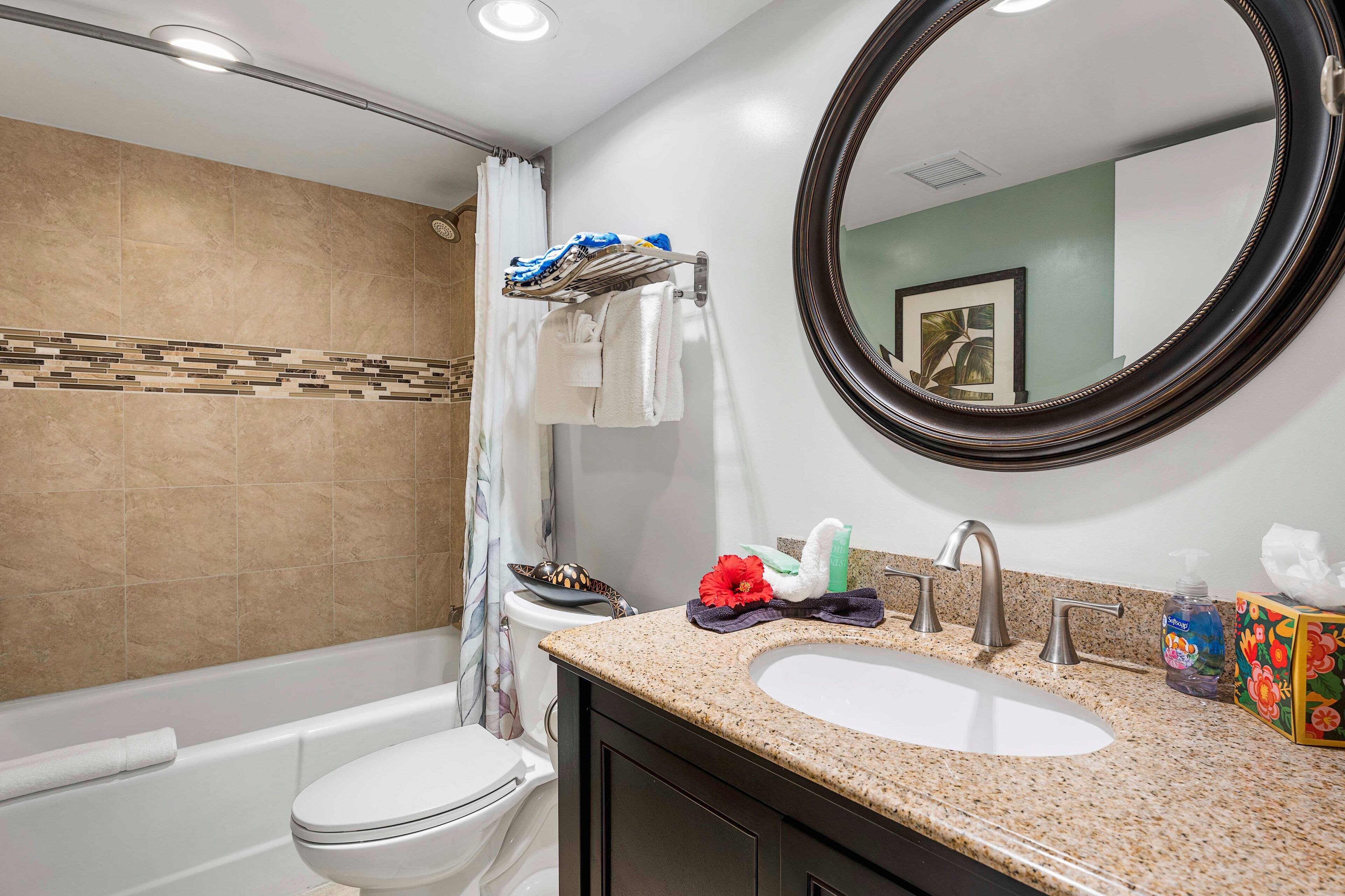 A bathroom with a bathtub, toilet, sink, and a large mirror.