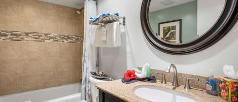 A bathroom with a bathtub, toilet, sink, and a large mirror.