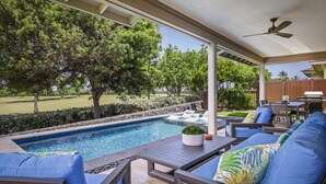 Un espacio al aire libre techado con piscina, sillas de descanso y una mesa de patio.