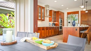 Una cocina moderna con armarios de madera, una isla central y un comedor con una mesa dispuesta para el desayuno.
