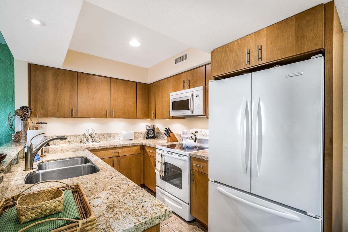 A modern kitchen with wooden cabinets, a stainless steel refrigerator, a microwave, and a stove.