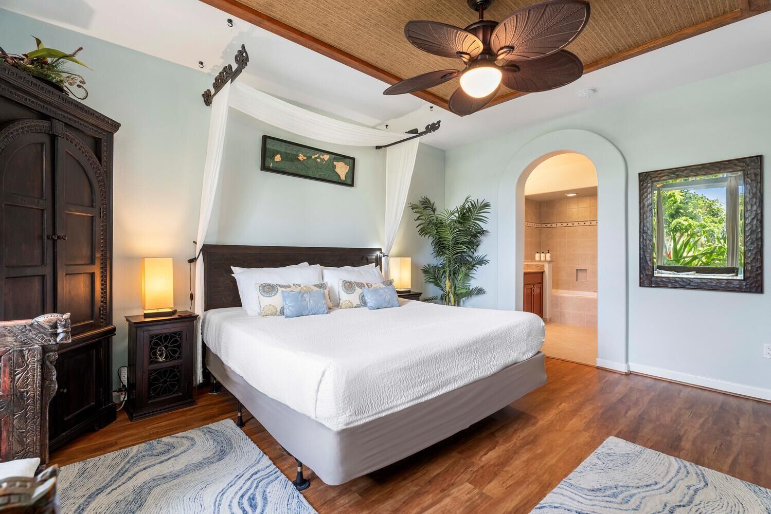 A spacious bedroom with a large bed, a ceiling fan, and a view of a bathroom.