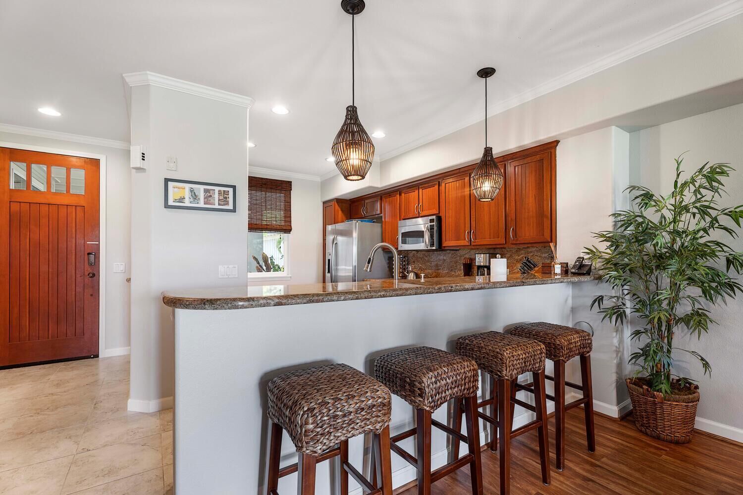 Una cocina con armarios de madera, encimera de granito y una isla central con taburetes de bar.
