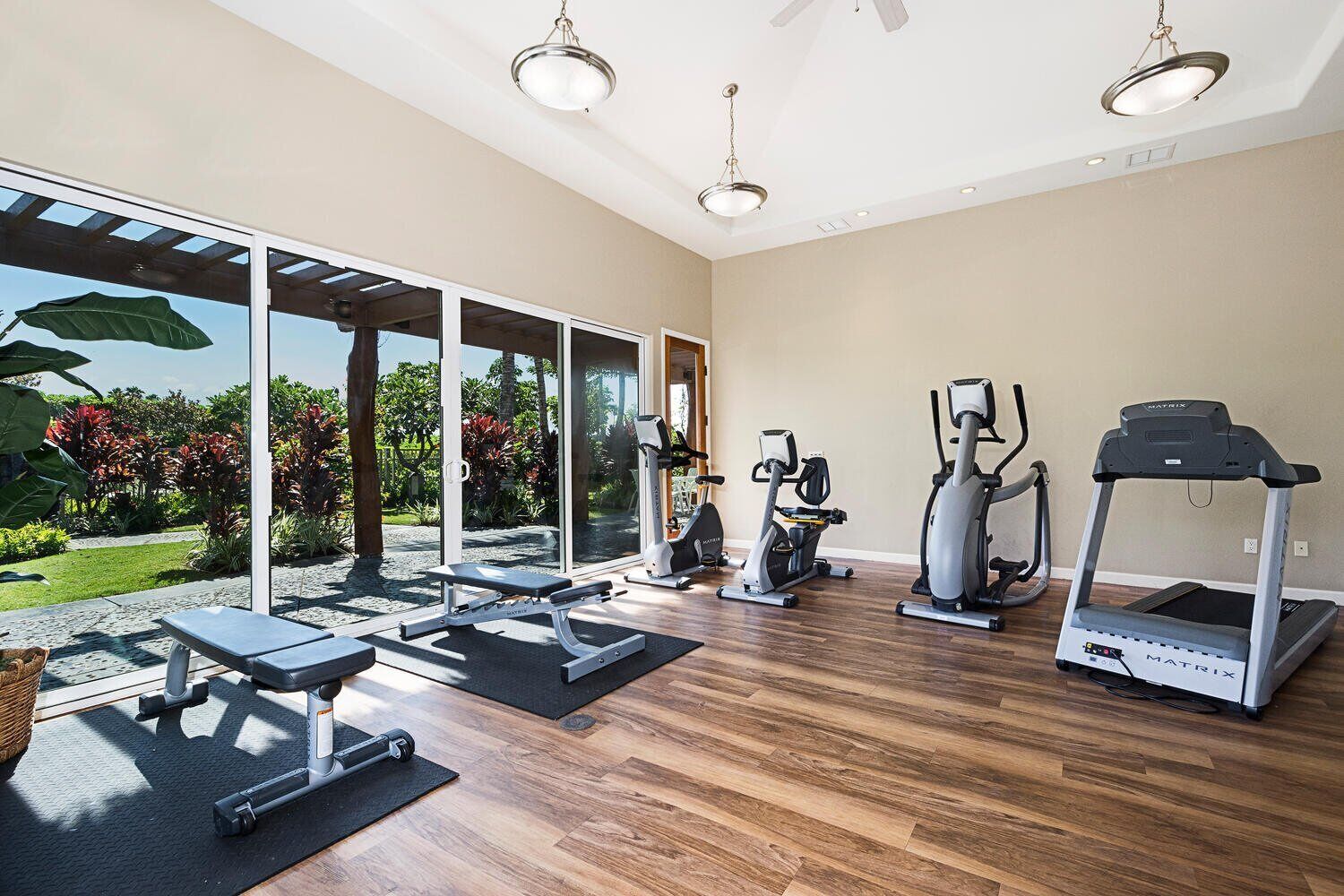 Une salle de sport spacieuse, équipée d’un tapis de course, d’un vélo elliptique et d’un banc de musculation.