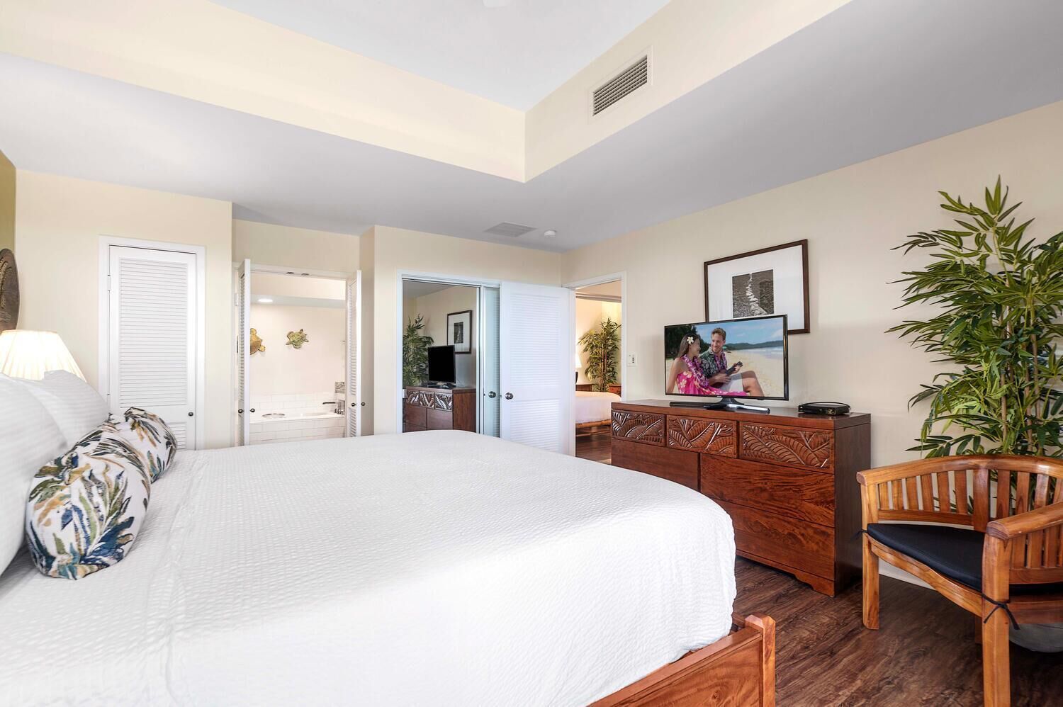 A hotel room with a large bed, a wooden dresser, a television, and a chair.