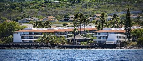Un hotel costero con varias edificaciones, algunas con techos rojos y otras con fachadas blancas, ubicado cerca de una masa de agua.