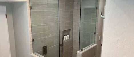 A modern bathroom with a glass-enclosed shower, tiled walls, and a towel rack.