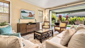 Un salon comprenant un canapé, des fauteuils, une table basse, un meuble et un tableau.