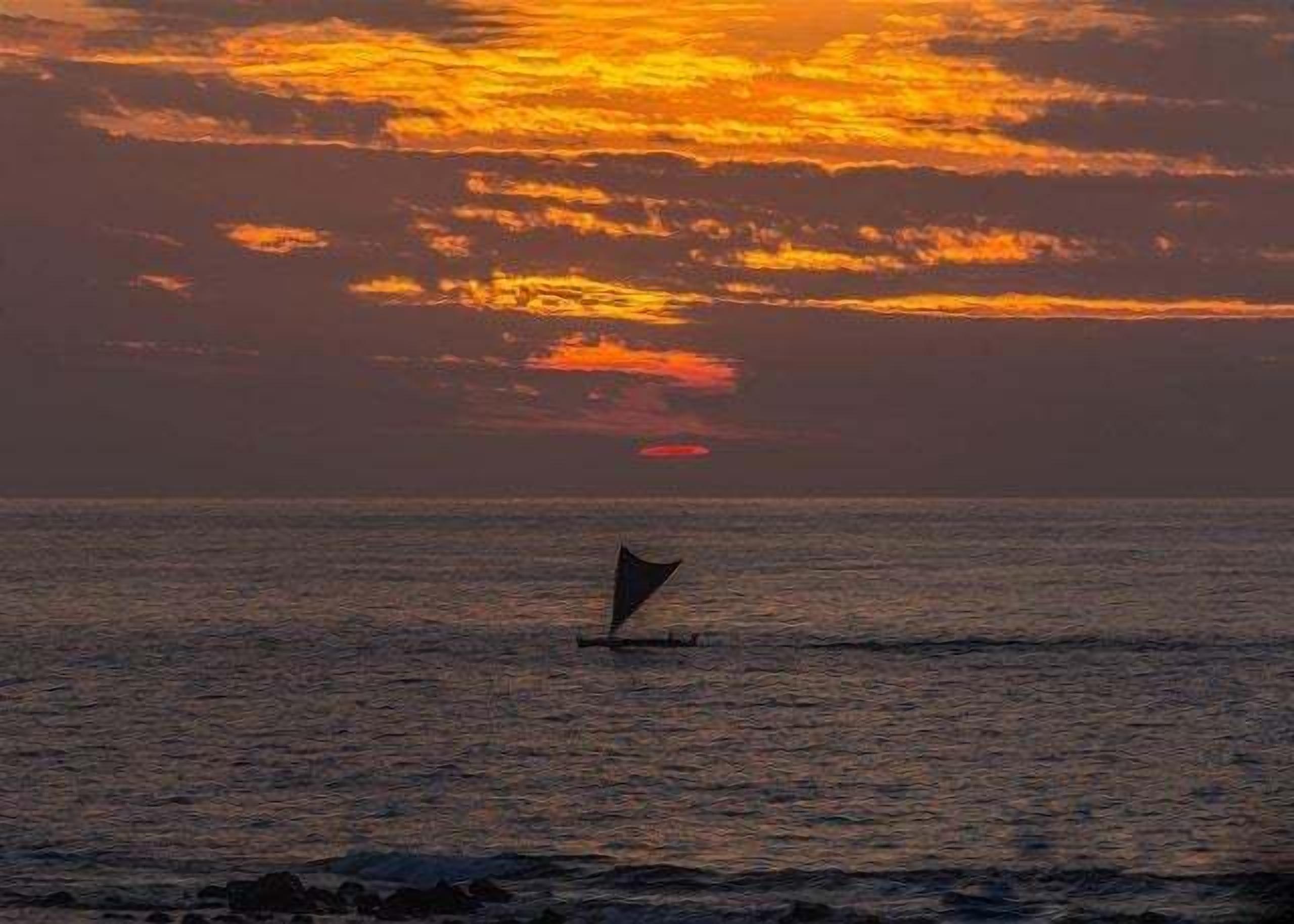 A sailboat on calm waters during sunset.