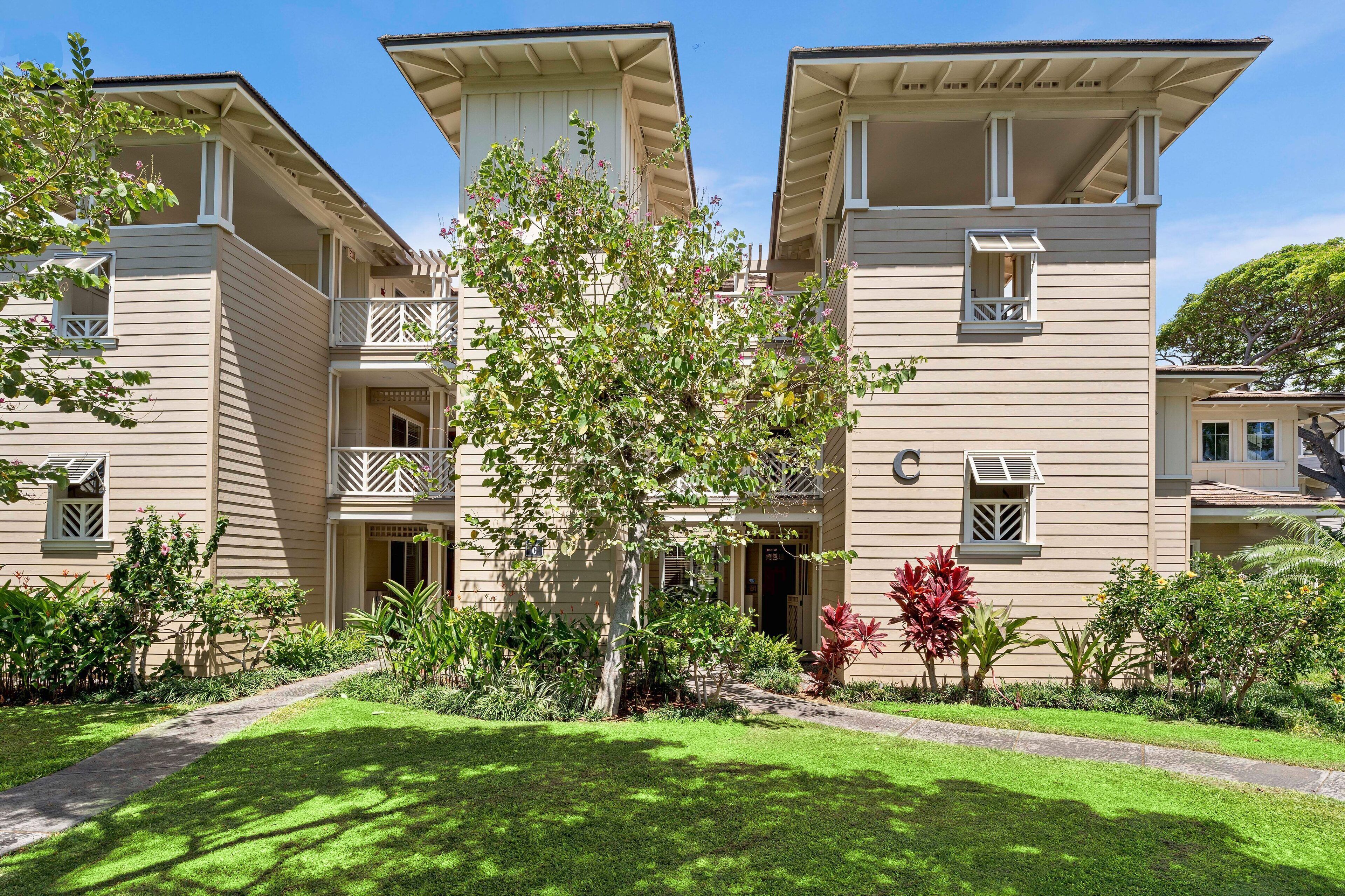 A multi-story building with balconies and a well-maintained garden.