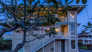 Una casa de dos pisos con balcón, escaleras y un pequeño porche.