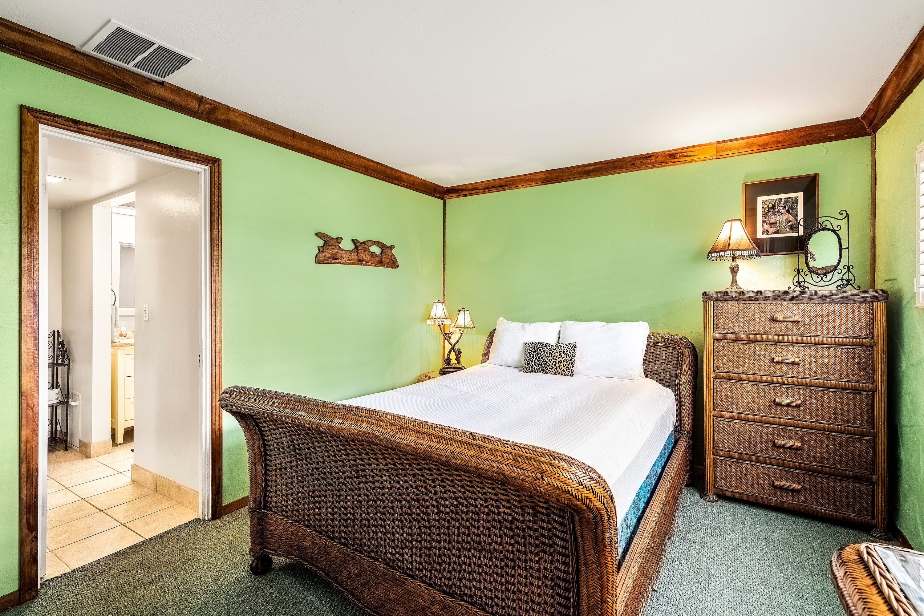 A bedroom with a large bed, a dresser, and a mirror.