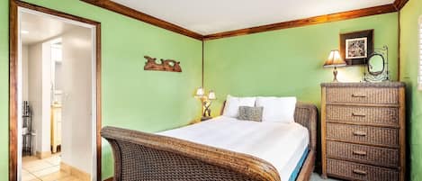A bedroom with a large bed, a dresser, and a mirror.