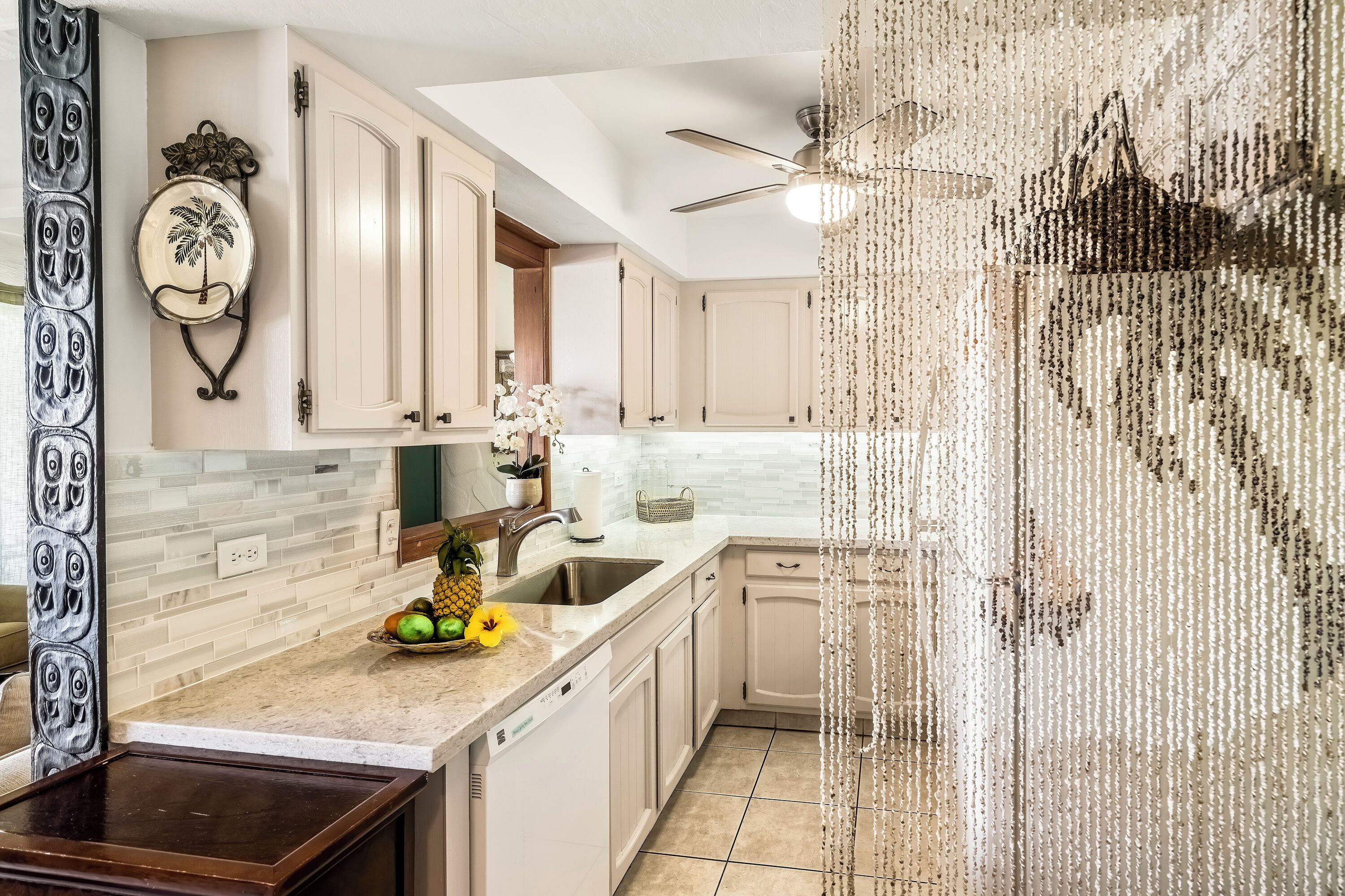 A kitchen with white cabinets, a granite countertop, and a ceiling fan.