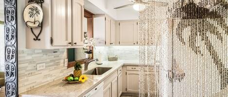 A kitchen with white cabinets, a granite countertop, and a ceiling fan.
