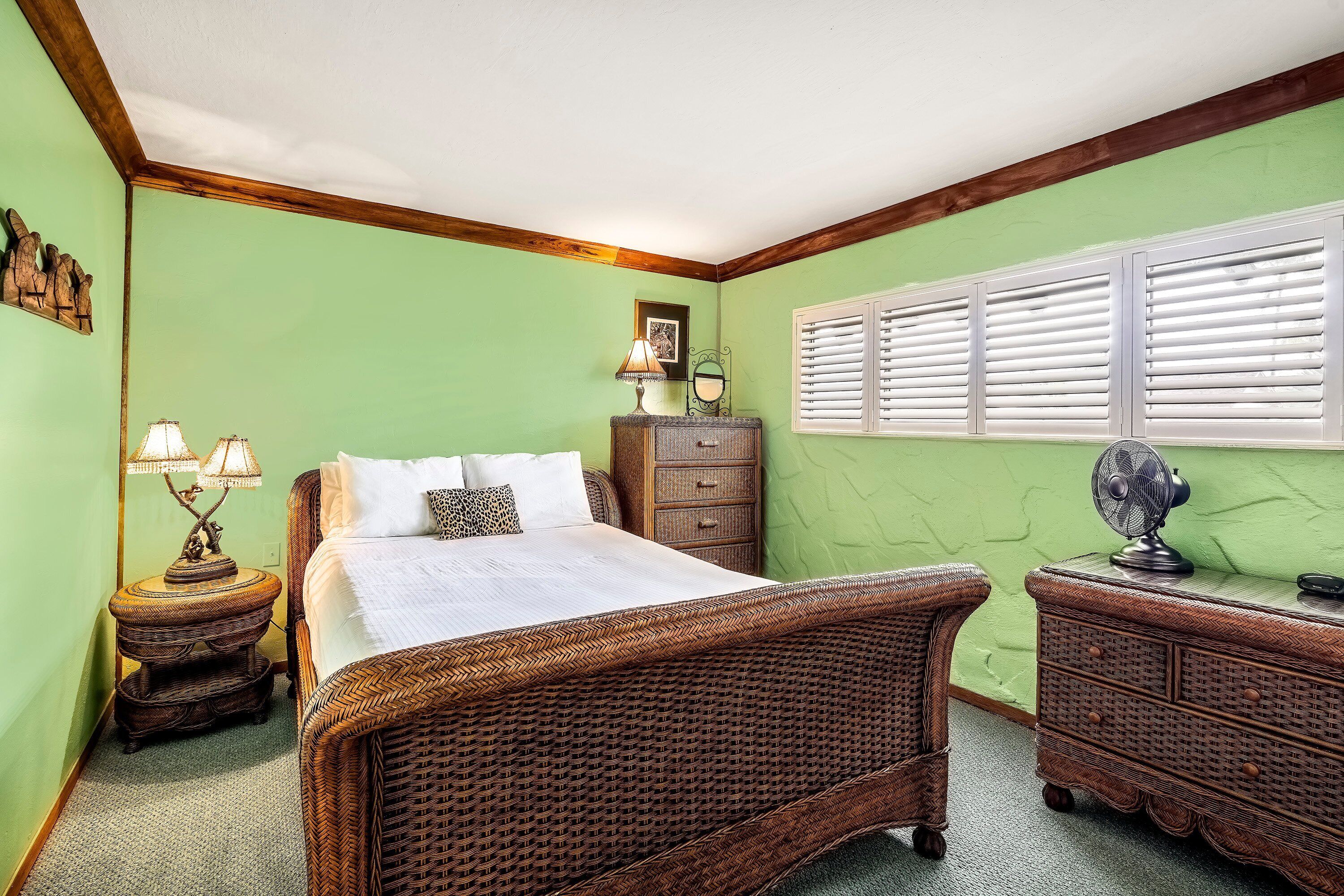 A room with a bed, a dresser, a nightstand, and a window with blinds.