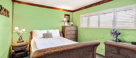 A room with a bed, a dresser, a nightstand, and a window with blinds.