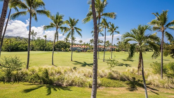 A golf course with palm trees and a building in the background.