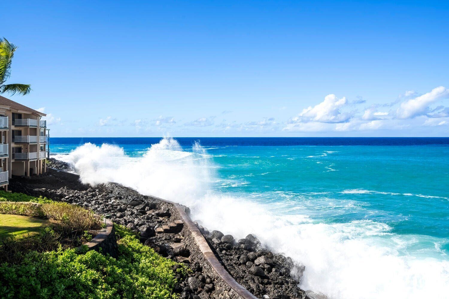 A coastal hotel with a rocky shoreline and waves crashing against the rocks.
