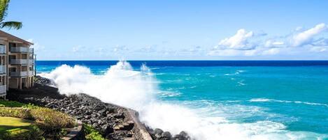 A coastal hotel with a rocky shoreline and waves crashing against the rocks.