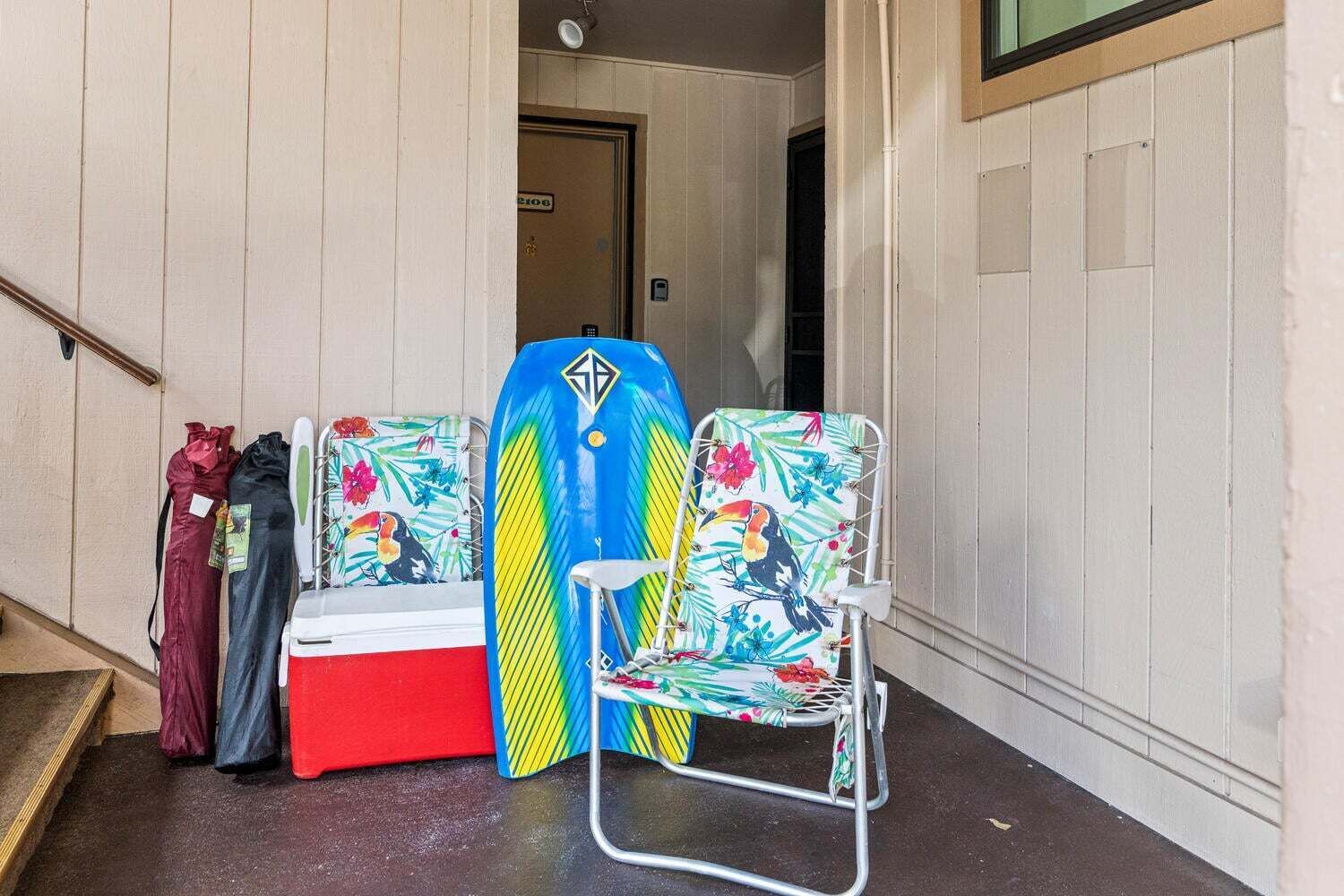 A hallway with a surfboard rack, a cooler, and a chair.