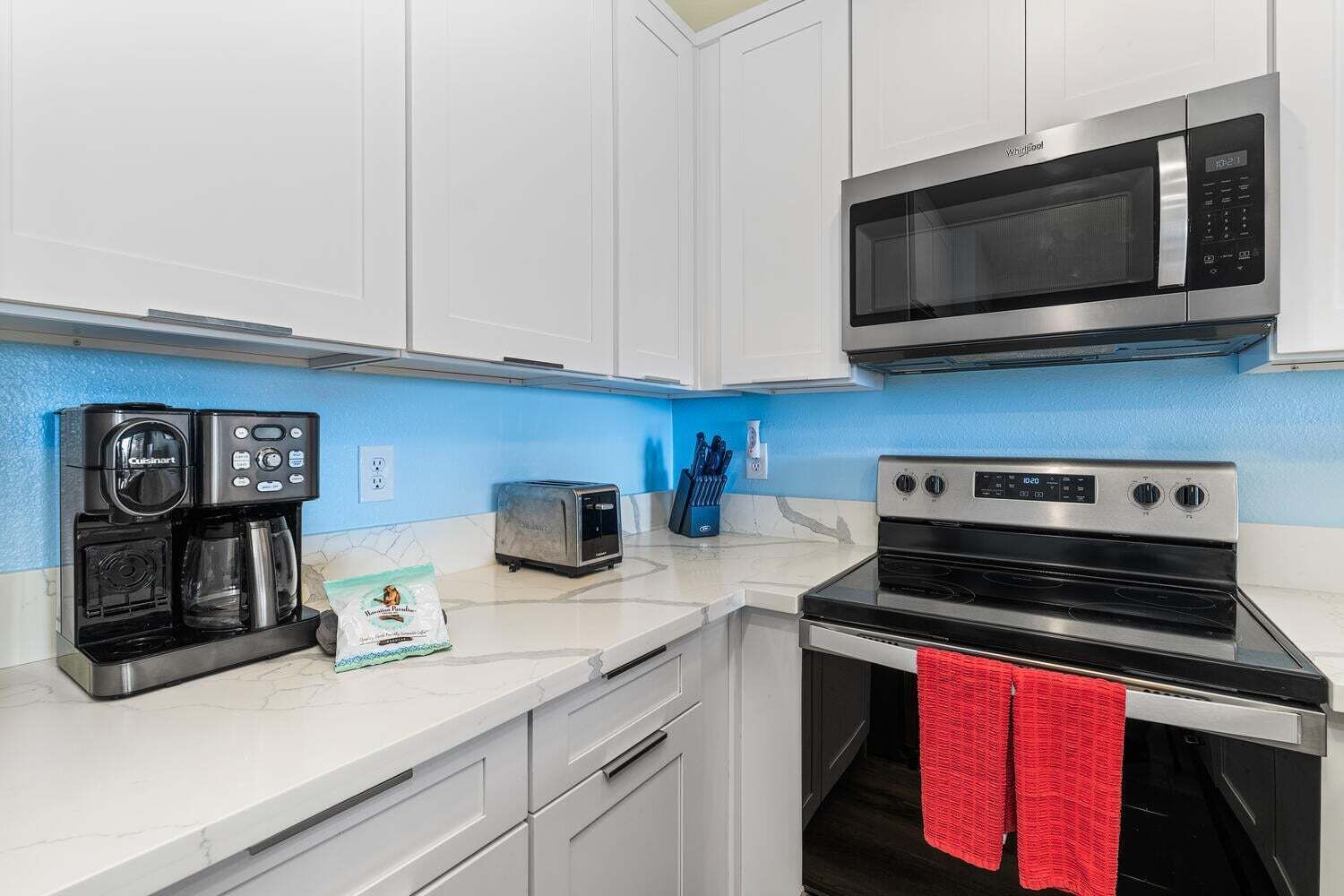 A compact kitchen with a coffee maker, toaster, microwave, and oven.