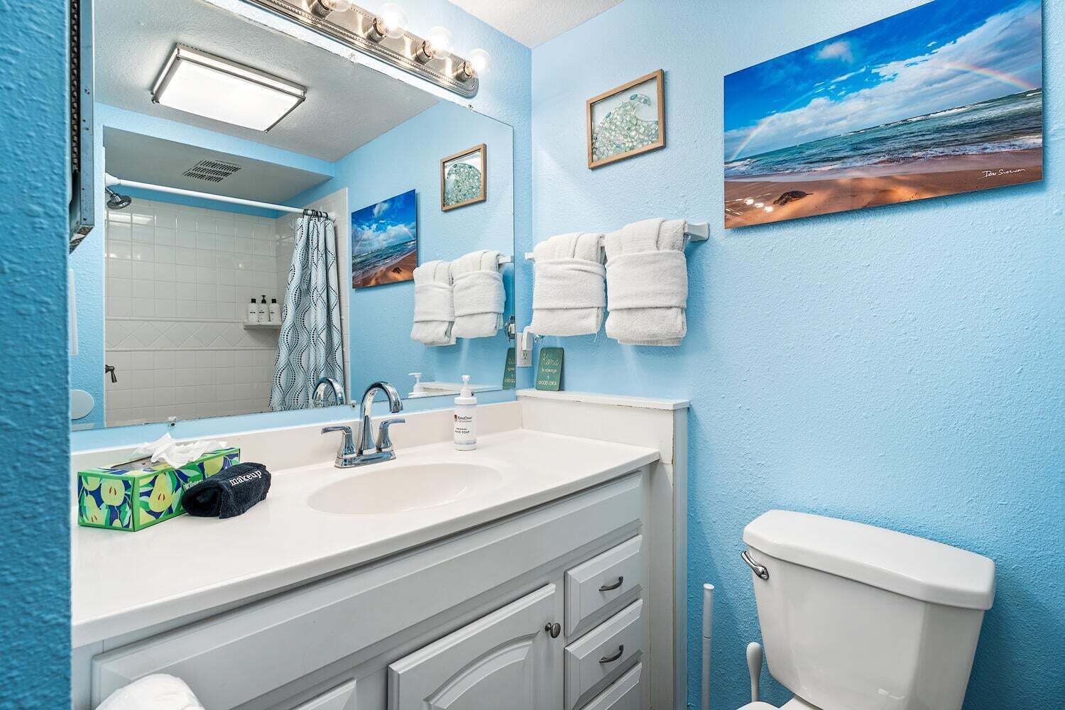 Une salle de bain avec un lavabo blanc, un miroir, des toilettes et des serviettes accrochées au mur.