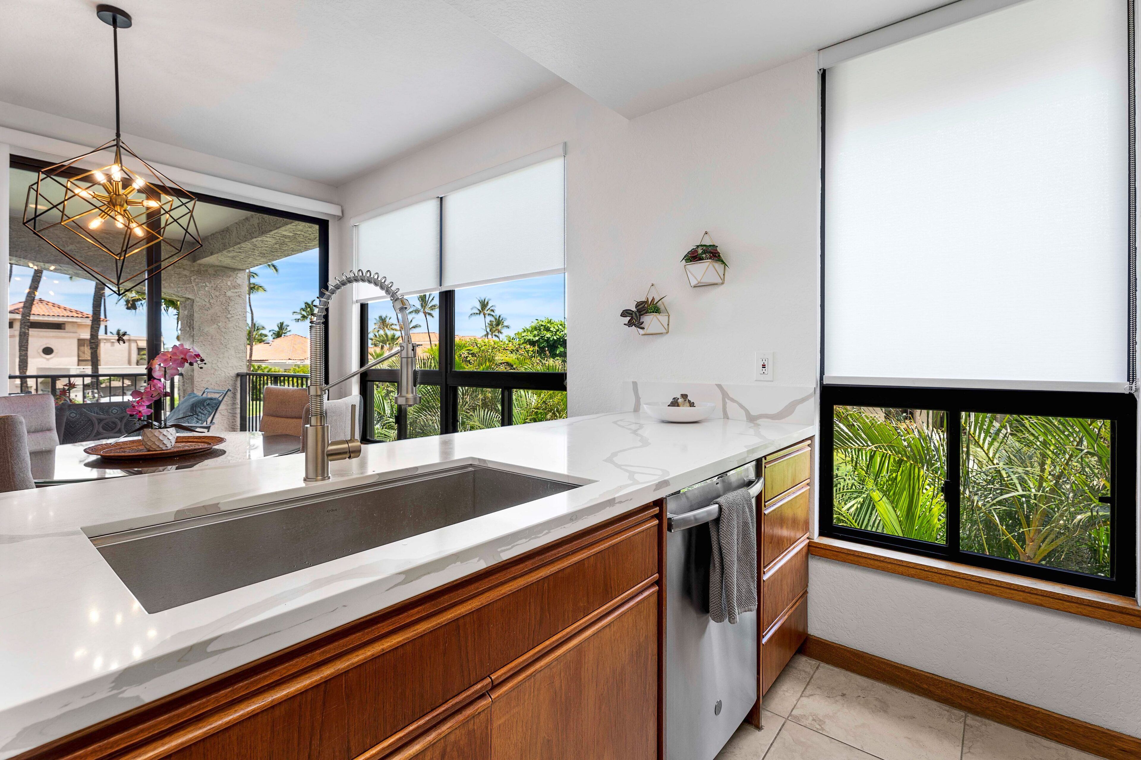 A modern kitchen with a large island, built-in appliances, and large windows offering a view of greenery.