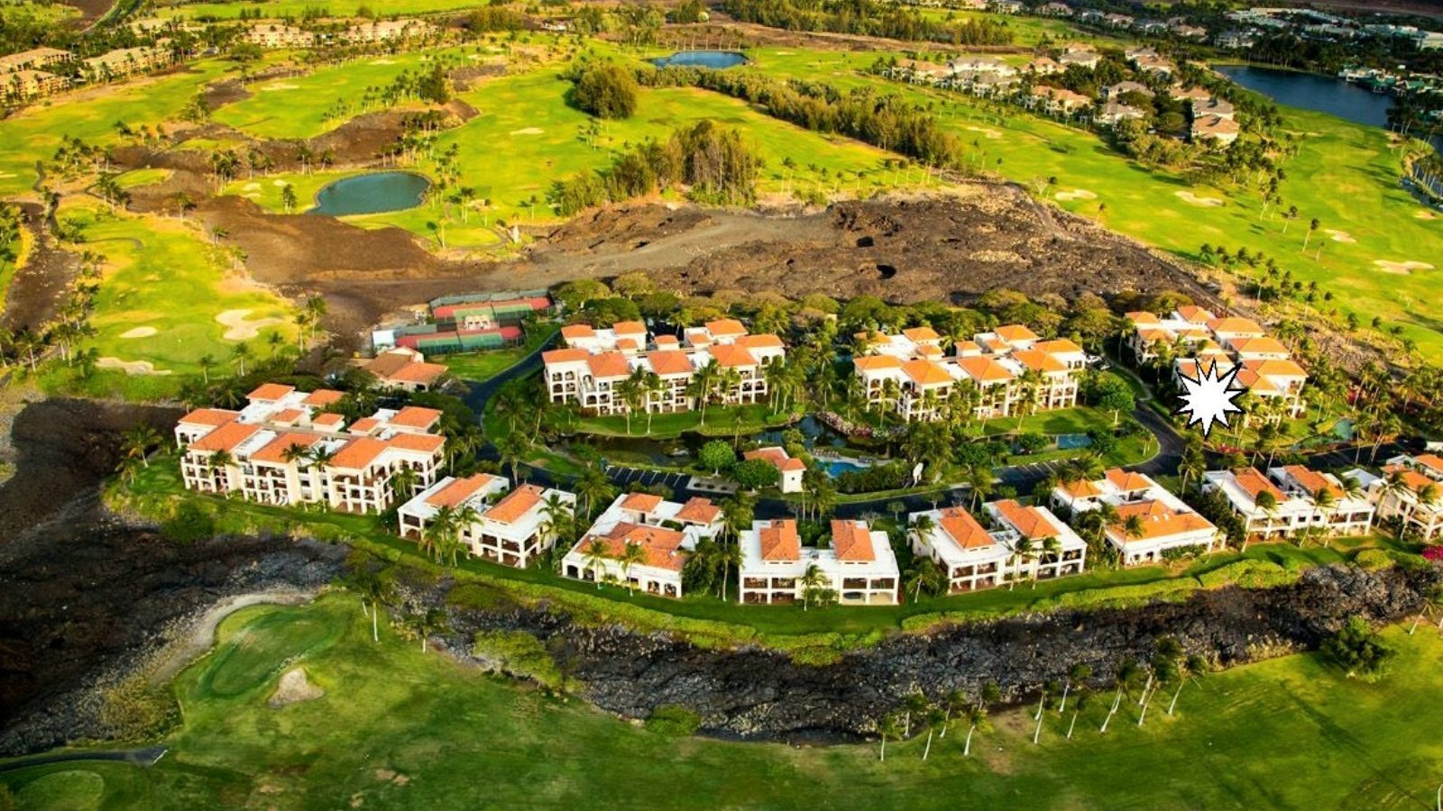 Luchtbeeld van een resort met meerdere gebouwen, een golfbaan en een waterpartij.