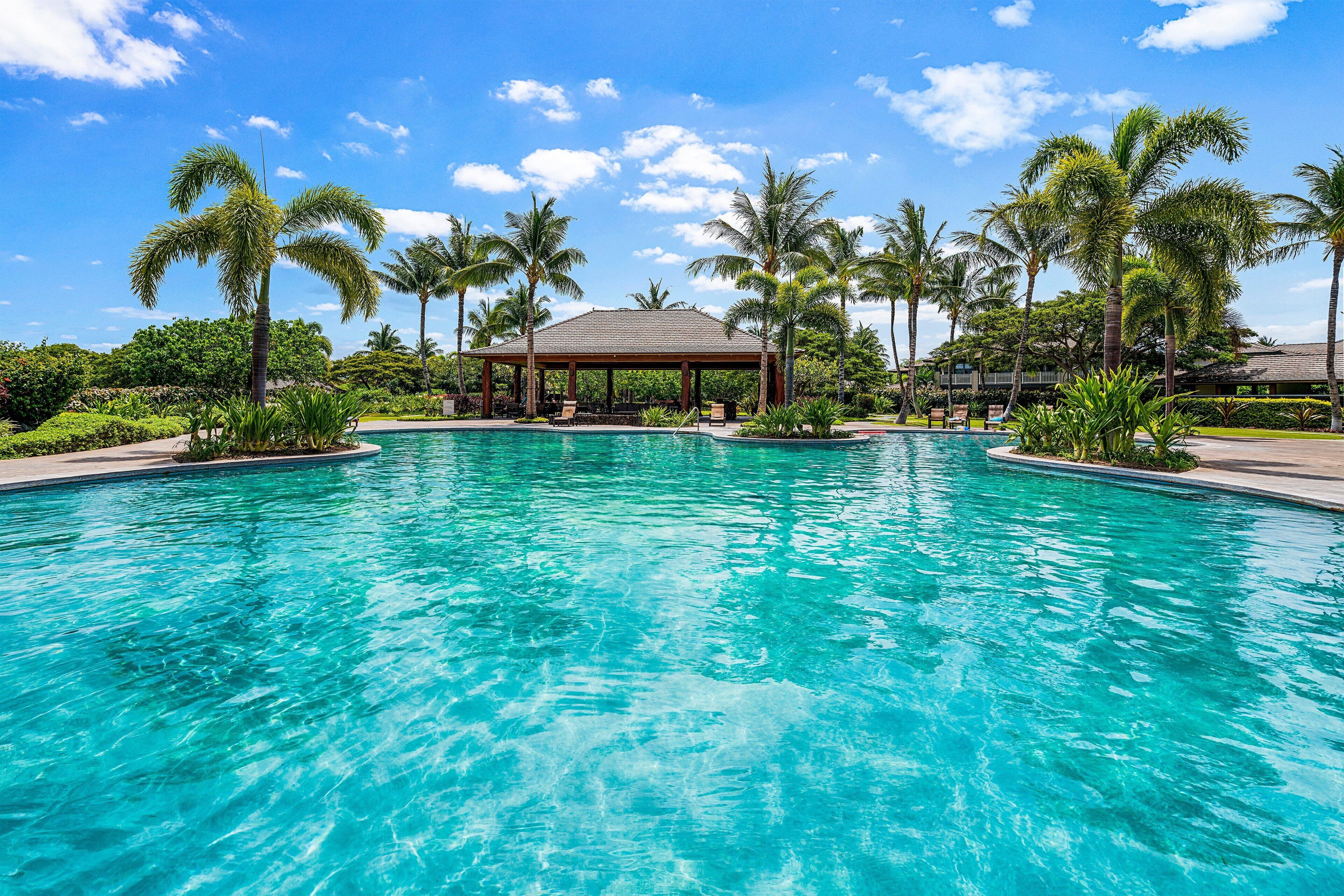 A clear blue pool with a gazebo and palm trees in the background.