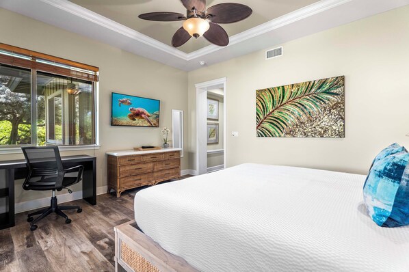 A bedroom with a large bed, a desk with a chair, a dresser, and artwork on the walls.