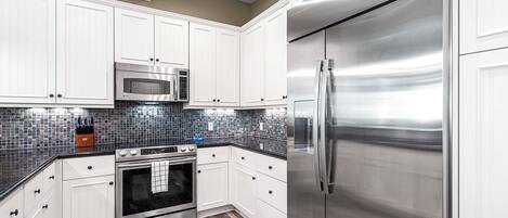 A kitchen with white cabinets, stainless steel appliances, and a tiled backsplash.