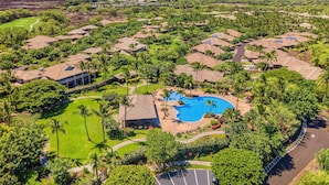 An aerial view of a resort with multiple bungalow-style buildings, a central swimming pool, and lush greenery. - Beautiful Townhome - Great Location & Amenities - Vrkcv (Kamuela)