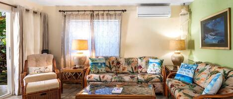 A living room with a sofa, armchairs, a coffee table, and a lamp.