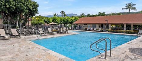 Una piscina con sillas de descanso y un patio de piedra.