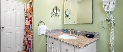 Un baño con un lavabo blanco, dos espejos, un secador de pelo y un perchero para toallas.