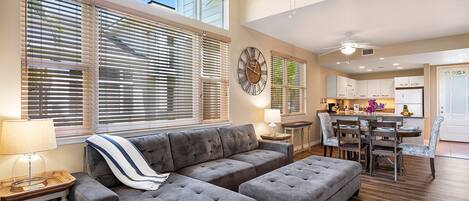 A spacious living room with a sectional sofa, ottoman, and dining area with a table and chairs.