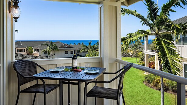 A balcony with a table and chairs, overlooking a view of the ocean and neighboring houses. - Concierge Included - Ocean View - Walk to Beach - Central AC - Vrkcv (Kailua-Kona)