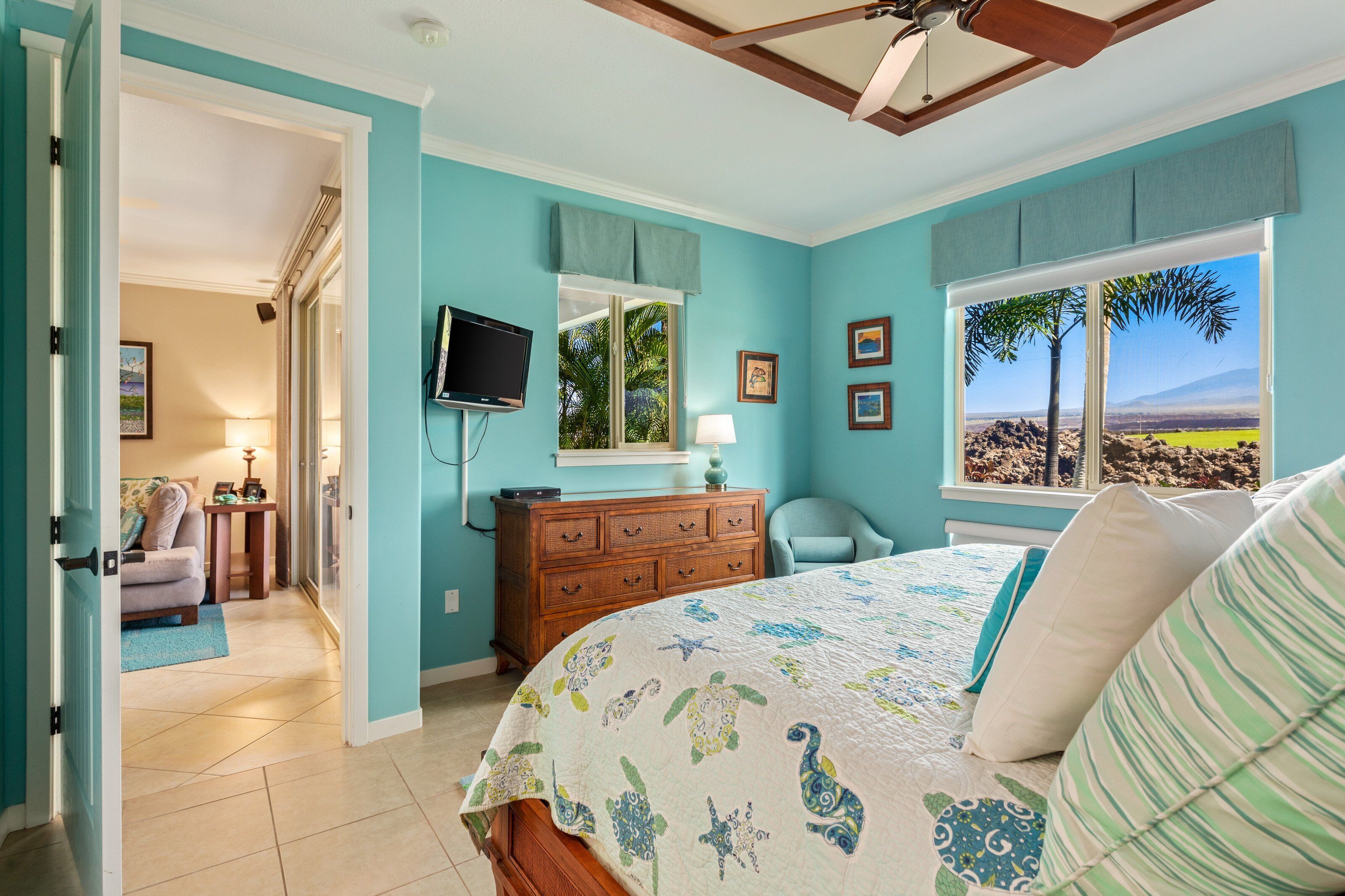 A bedroom with a bed, a dresser, a TV, and a window with a view of a landscape.
