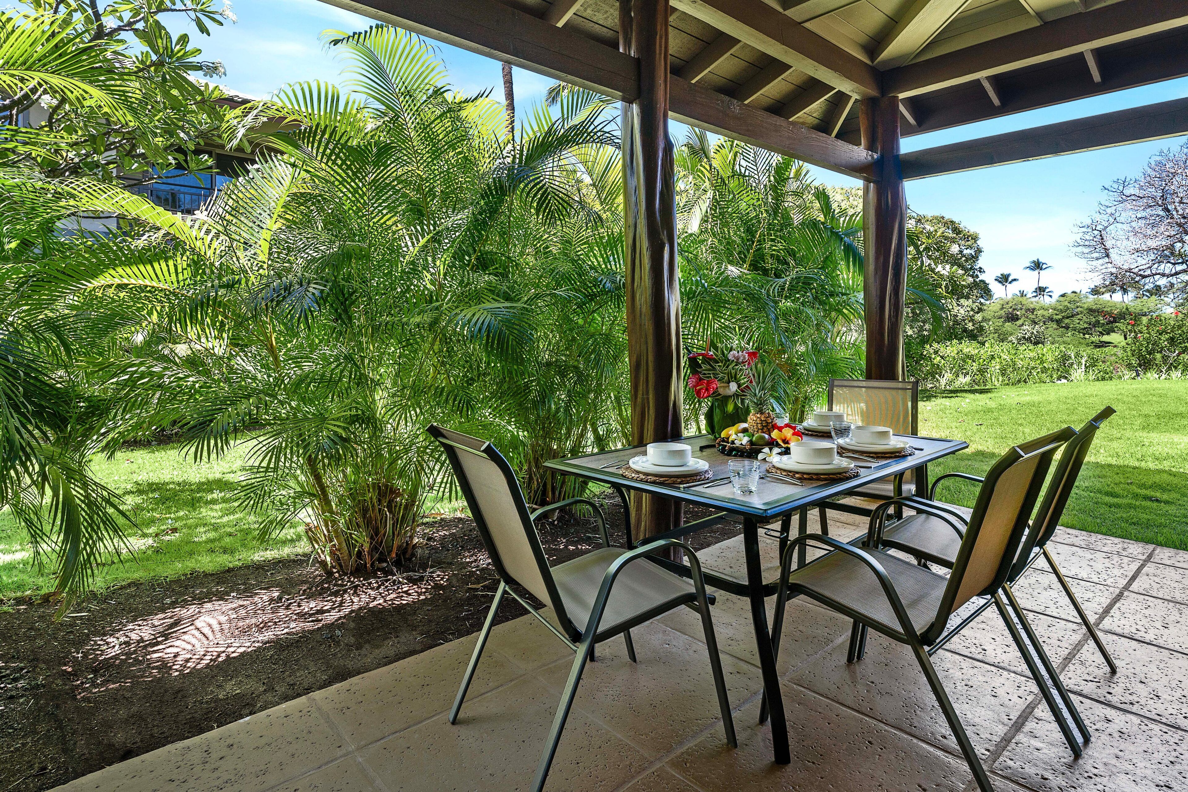 Une terrasse extérieure avec une table dressée pour le repas, entourée d’une végétation luxuriante et offrant une vue sur le paysage.