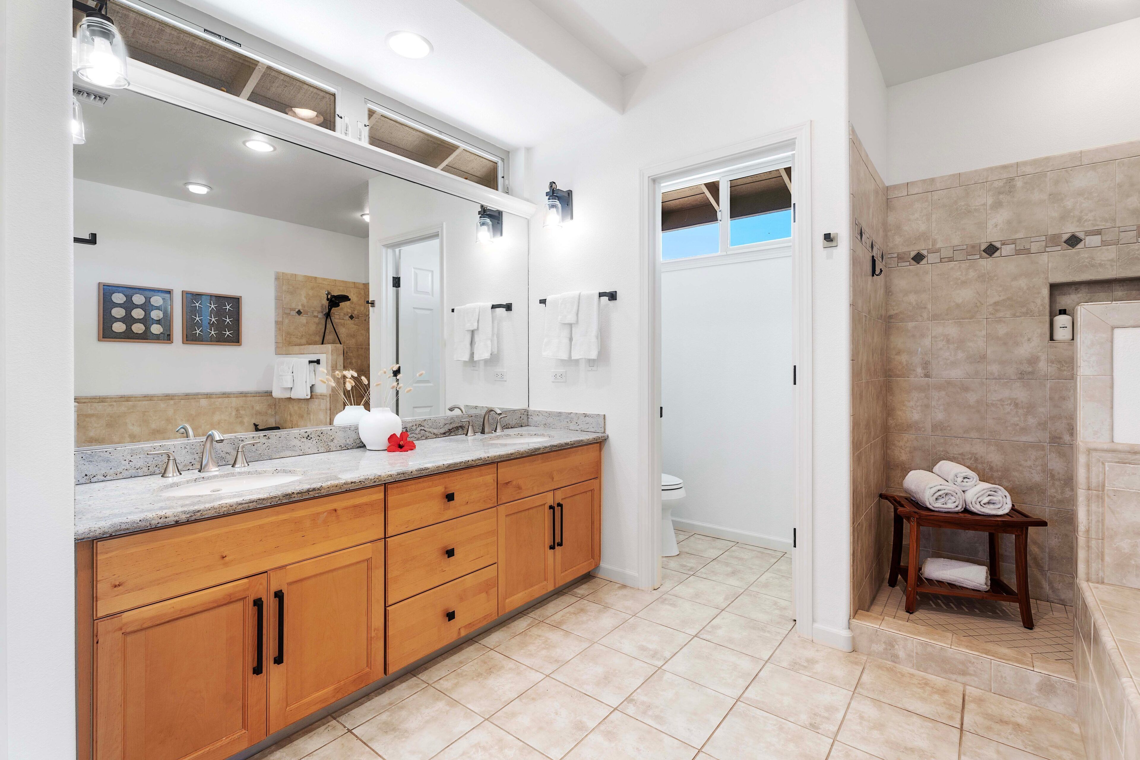 Une salle de bain moderne avec un grand miroir, des meubles en bois, un lavabo et un espace douche.