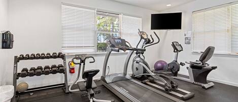 Un gimnasio con cintas de correr, mancuernas y equipo de ejercicio.