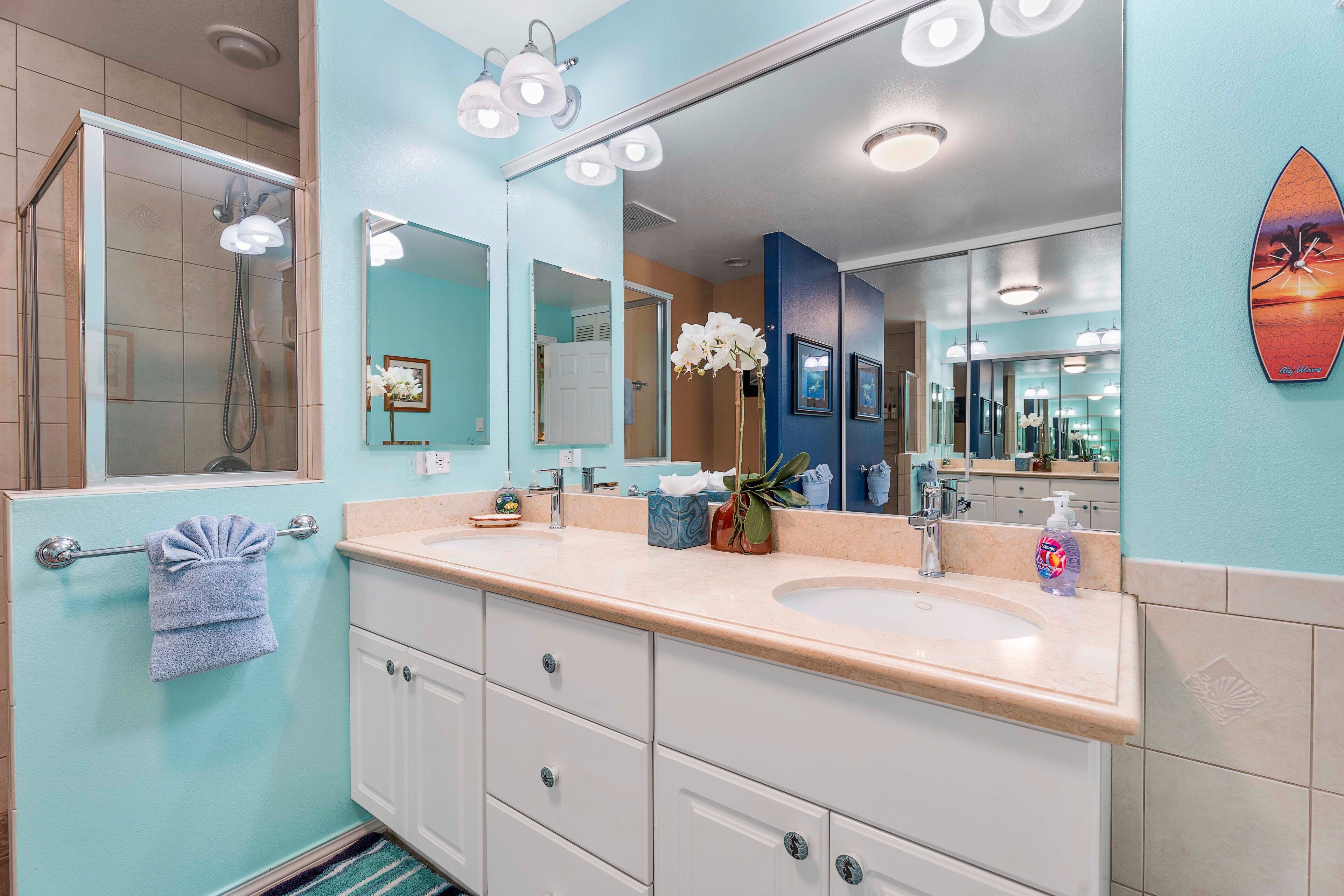 A bathroom with two sinks, a large mirror, and a shower.