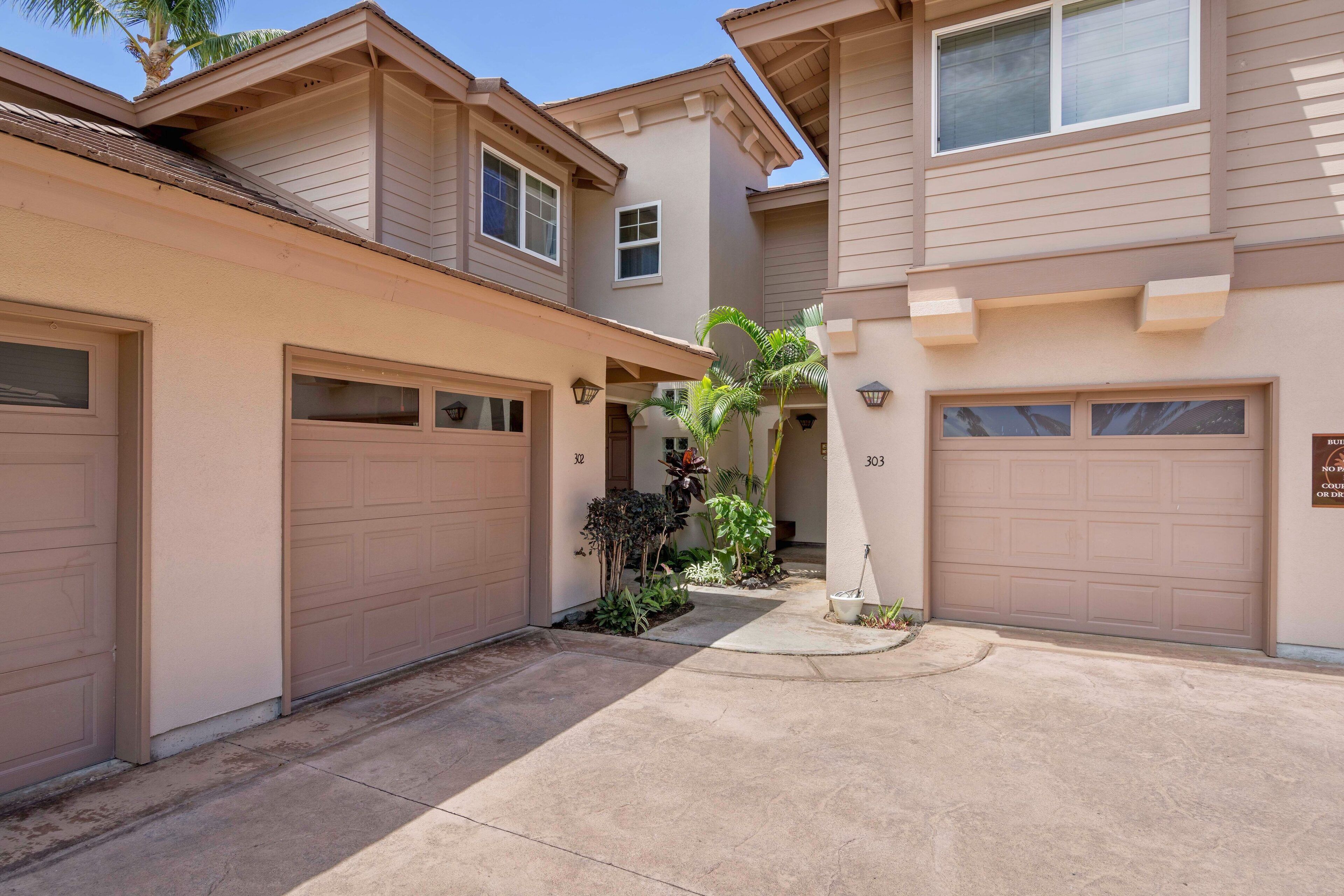 A residential building with two garages, numbered 303 and 32, and a small garden area with palm trees.