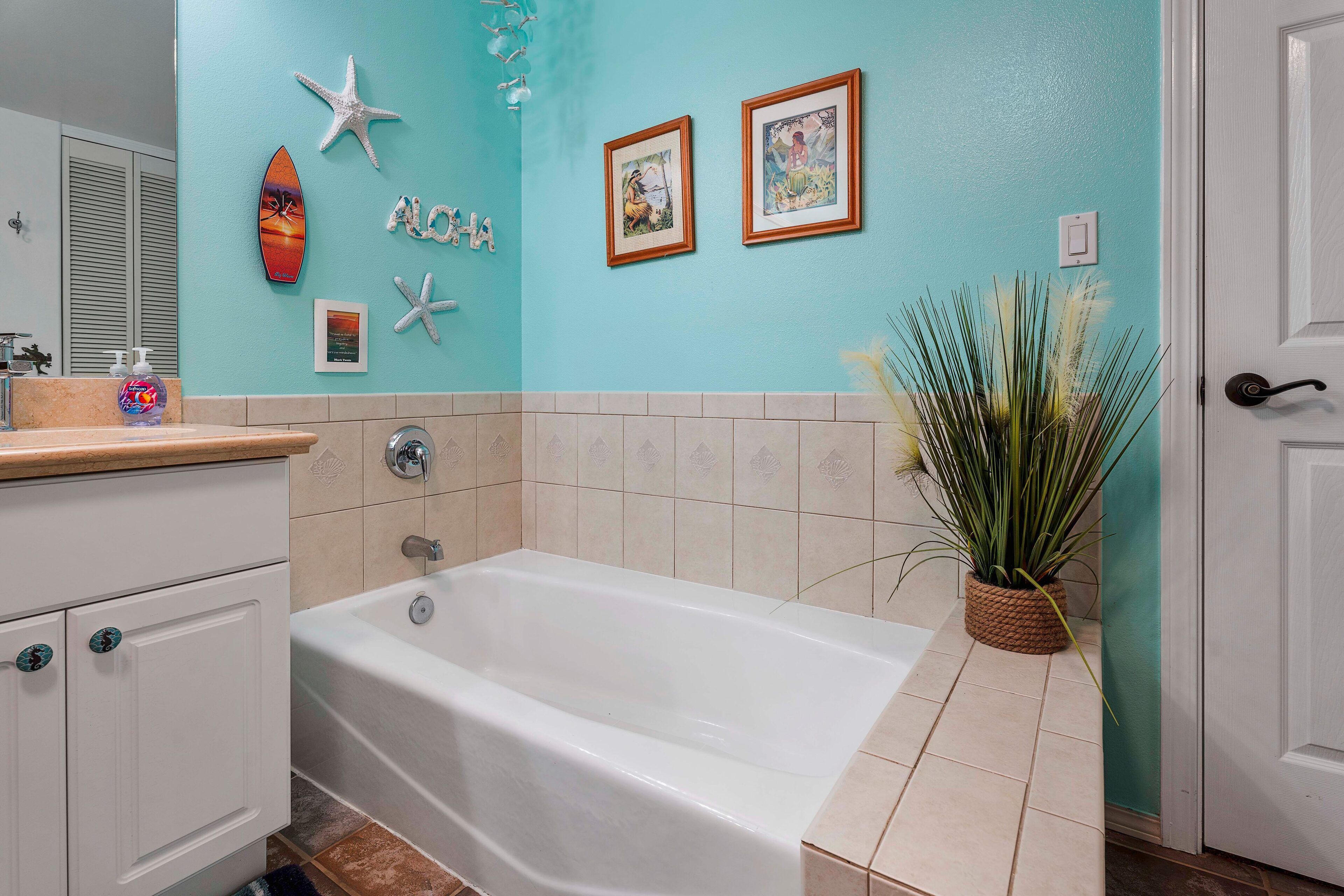 Une salle de bain avec une baignoire, un lavabo équipé de distributeurs de savon et des éléments décoratifs sur le mur.